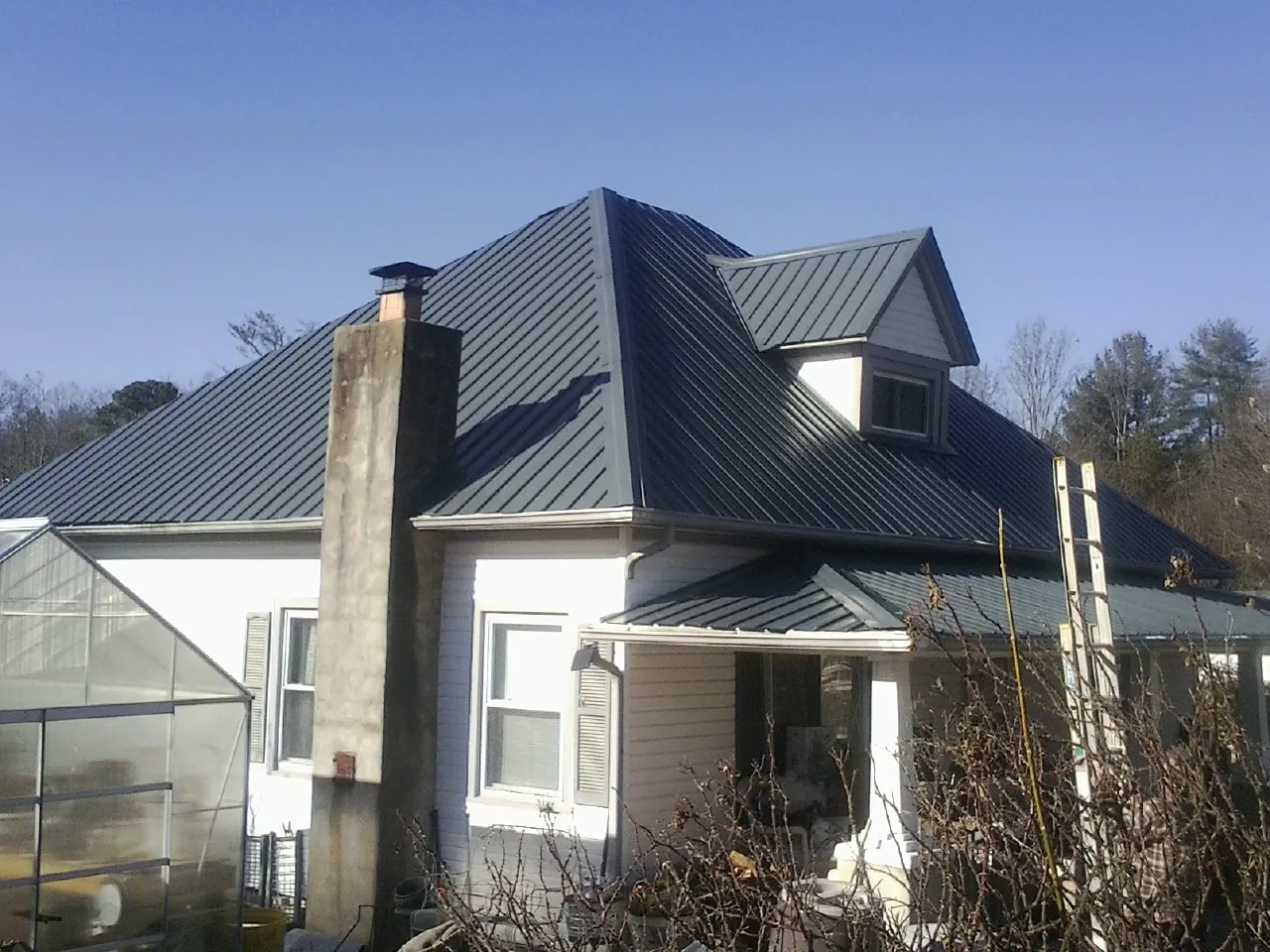 Dark blue standing seam metal roof on a white farmhouse with dormer — Slate & Tile Roof Repair by Roofing Brothers in Black Mountain