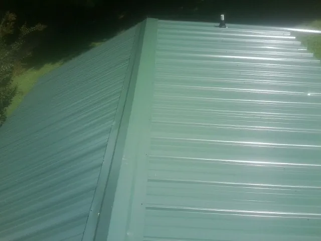 New green metal panels meeting at the ridge of a roof — Flat Roof Repair work by our crew in Black Mountain