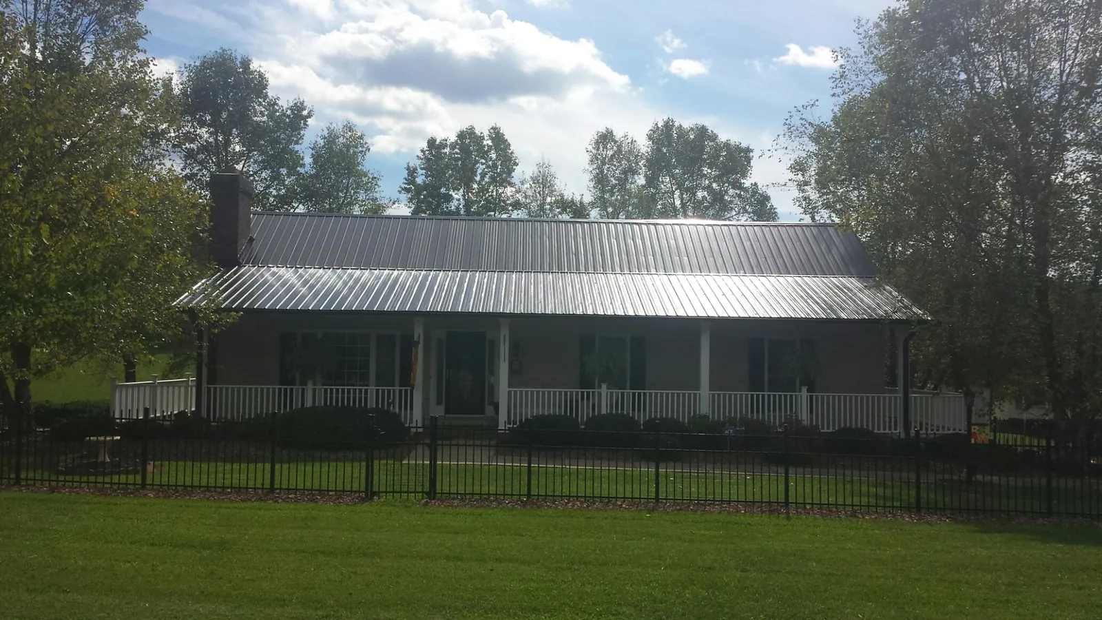 Gray metal roof on a brick ranch with a full width front porch — Gutter Guard Installation work by our crew in Black Mountain