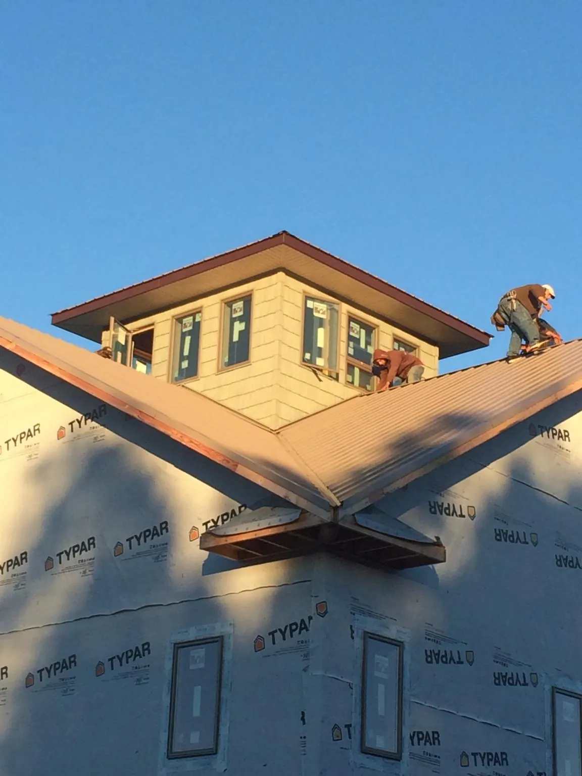 Roofers working around a rooftop cupola on a new metal roof at sunset — Roof Waterproofing in Black Mountain by Roofing Brothers